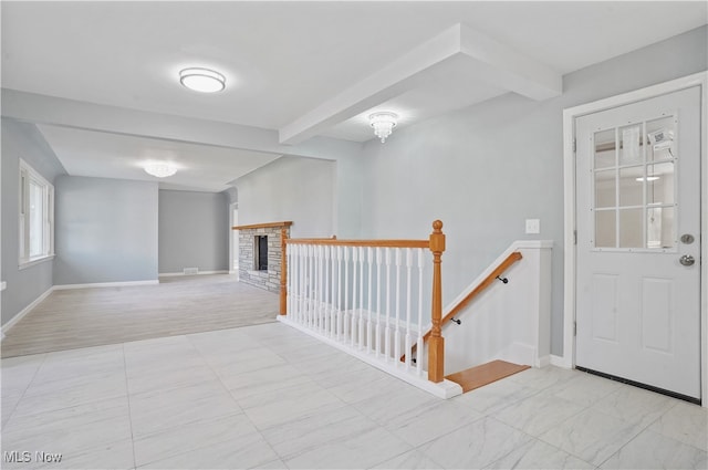 entryway featuring beamed ceiling and a fireplace