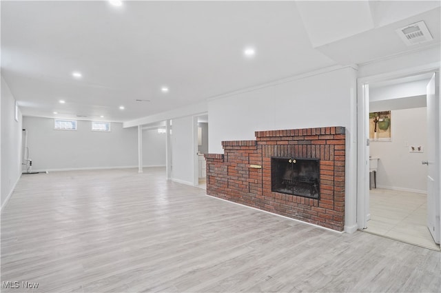 unfurnished living room with light hardwood / wood-style floors and a brick fireplace