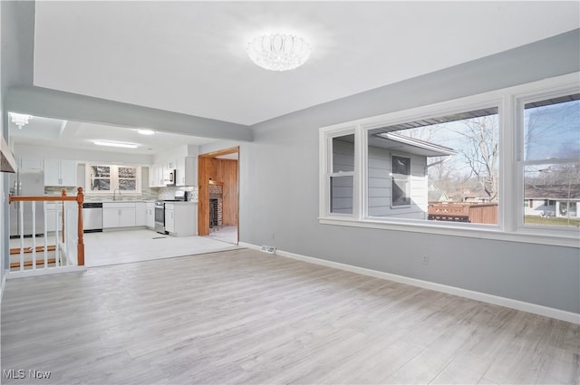 unfurnished living room with a notable chandelier, light hardwood / wood-style floors, and sink