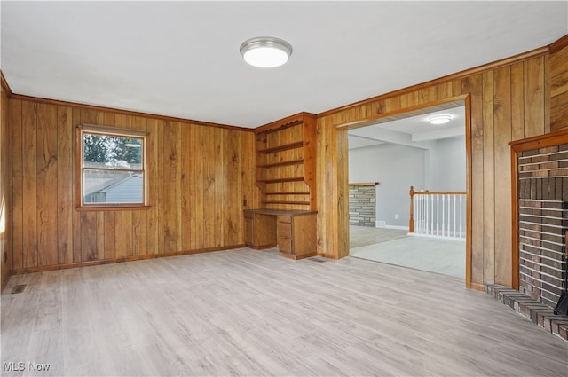 unfurnished living room with wood walls and light hardwood / wood-style floors