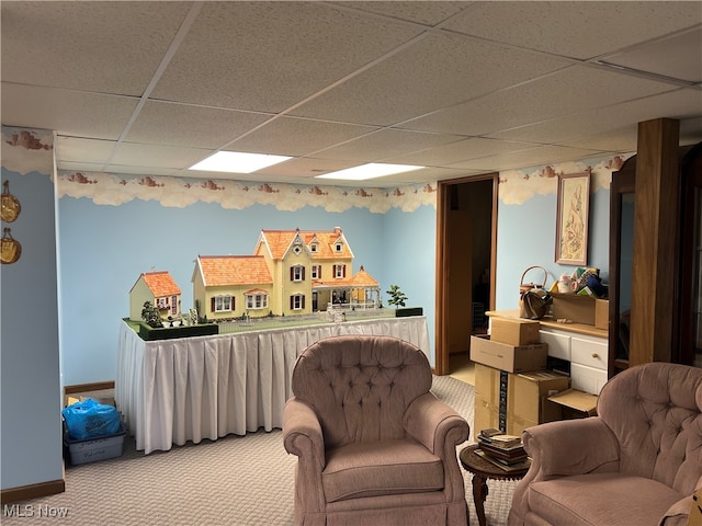 living area featuring light carpet and a paneled ceiling