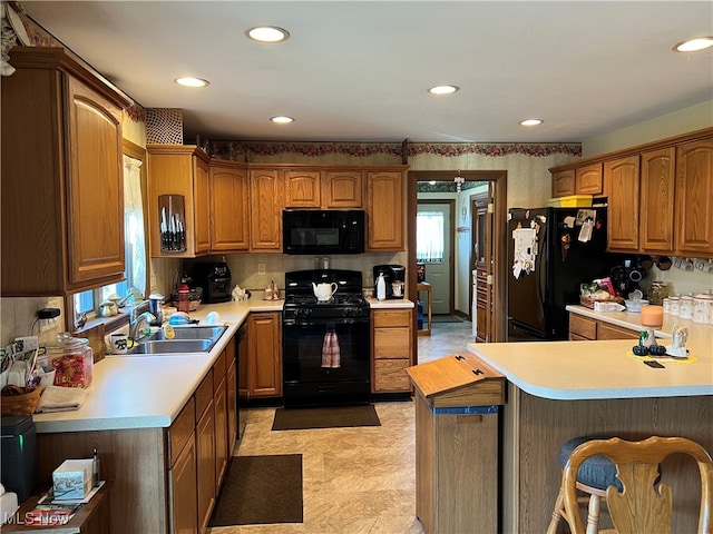 kitchen with a kitchen breakfast bar, kitchen peninsula, sink, and black appliances