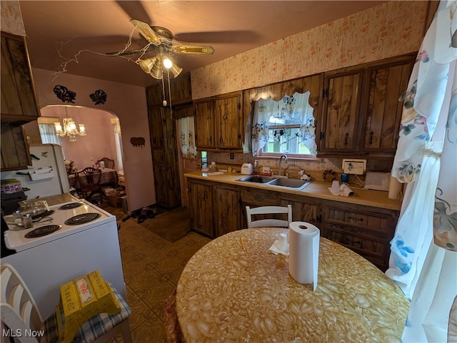 kitchen with white electric range, ceiling fan with notable chandelier, tasteful backsplash, and sink