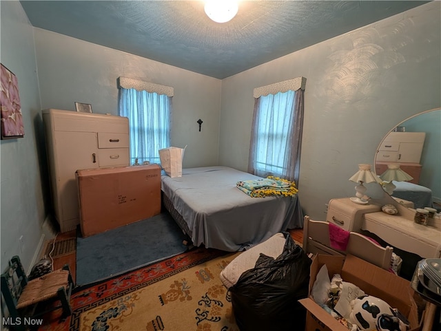 bedroom with a textured ceiling and multiple windows