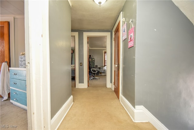 hall with light colored carpet and a textured ceiling