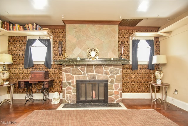 living room featuring dark hardwood / wood-style floors, a stone fireplace, and crown molding