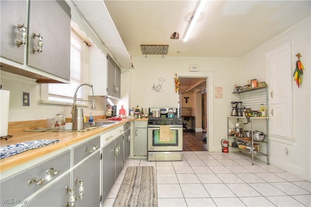 kitchen with light tile patterned floors, gas stove, gray cabinets, and sink