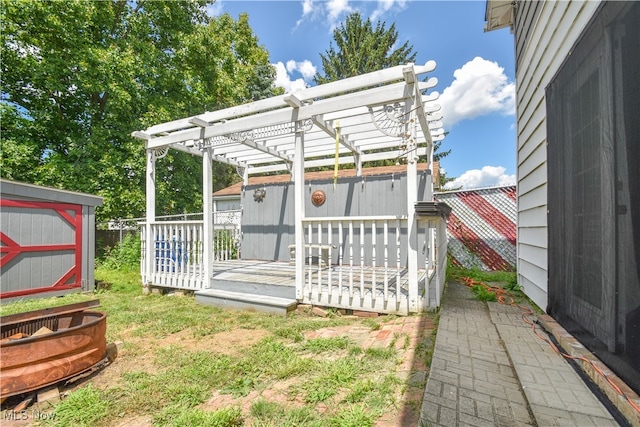 view of yard featuring a pergola, a deck, and a storage unit