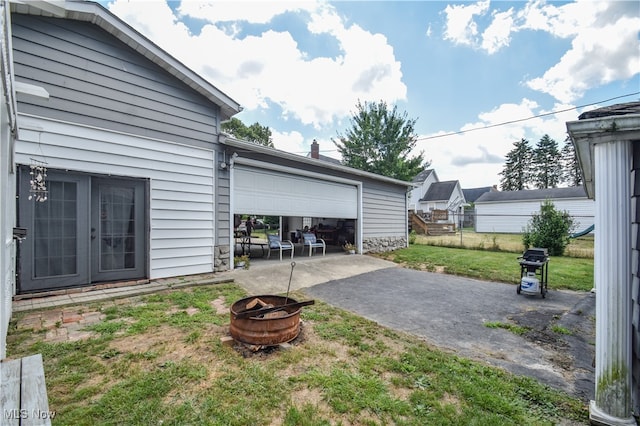 exterior space featuring a lawn, a fire pit, and a garage