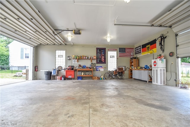 garage featuring a workshop area, white refrigerator, and a garage door opener