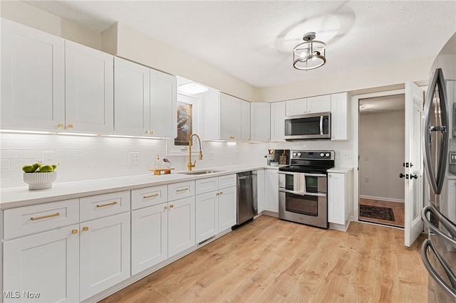 kitchen with white cabinets, stainless steel appliances, tasteful backsplash, and sink