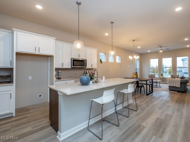 kitchen with white cabinets, an island with sink, and hanging light fixtures