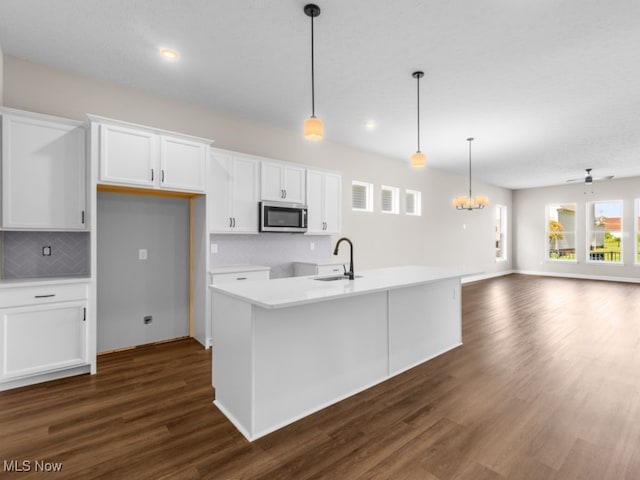 kitchen featuring dark hardwood / wood-style floors, white cabinetry, hanging light fixtures, and an island with sink