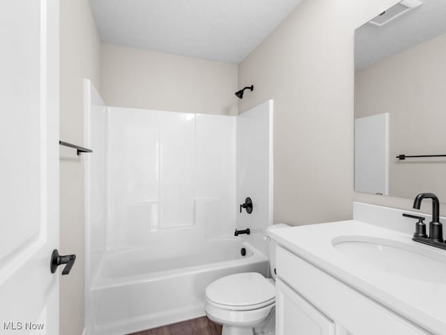 full bathroom with bathing tub / shower combination, a textured ceiling, toilet, vanity, and hardwood / wood-style flooring