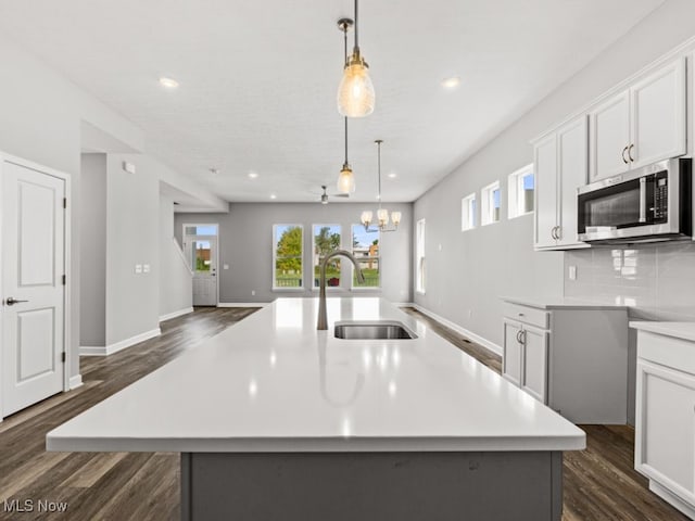 kitchen featuring pendant lighting, a center island with sink, dark hardwood / wood-style floors, and sink