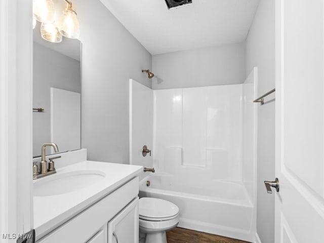 full bathroom with hardwood / wood-style floors, vanity, shower / bathtub combination, and toilet