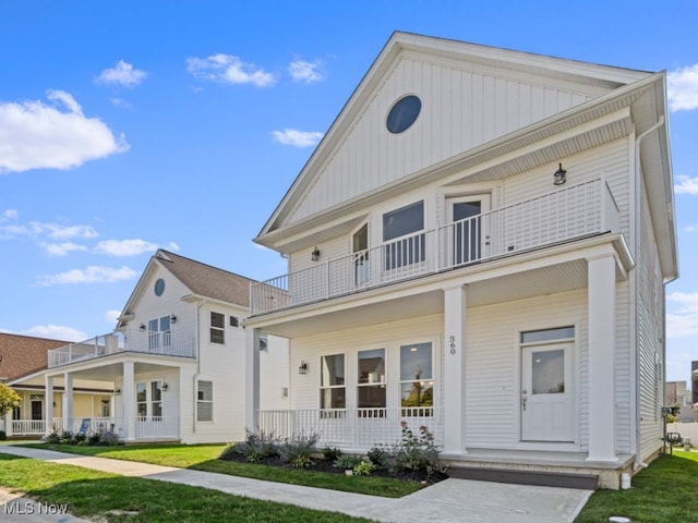 view of front facade featuring covered porch, a balcony, and a front yard