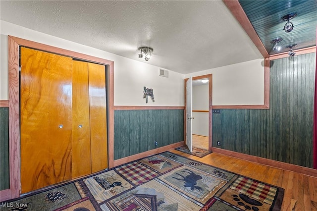 entryway with wood-type flooring, a textured ceiling, and wooden walls