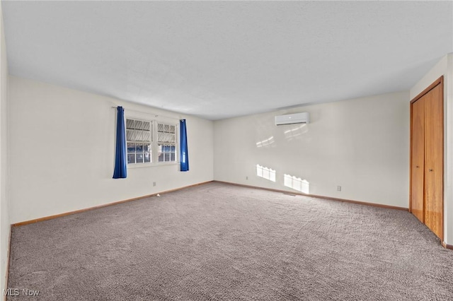 spare room with a wall mounted AC and carpet