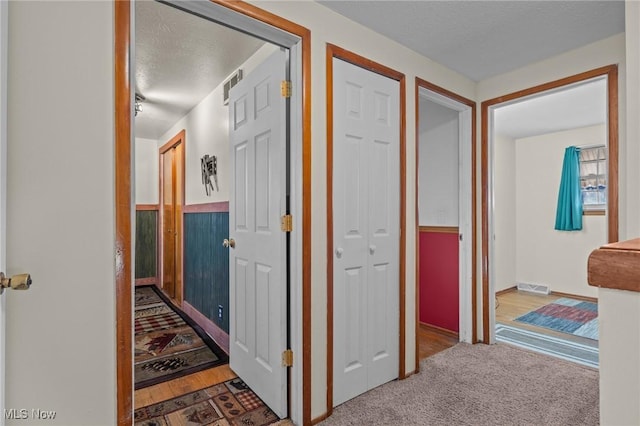 hallway with a textured ceiling and hardwood / wood-style flooring