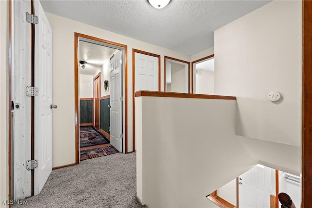 hallway with light colored carpet and a textured ceiling