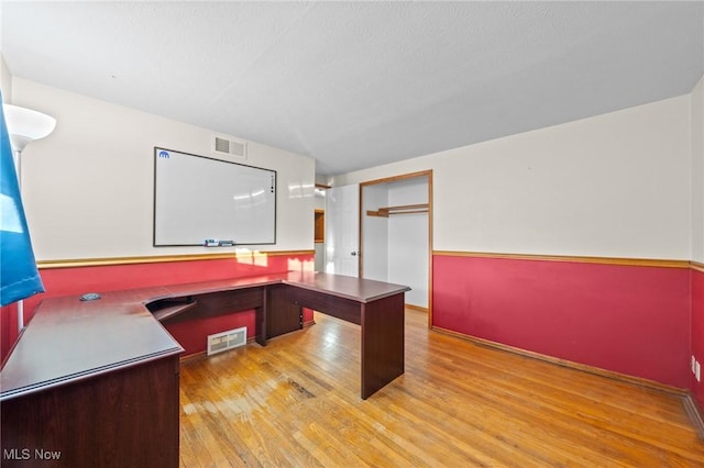 home office with a textured ceiling and light wood-type flooring