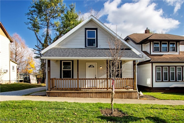 bungalow featuring covered porch, a front lawn, and roof with shingles