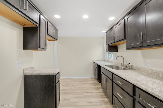 kitchen with light wood finished floors, baseboards, light countertops, dark brown cabinets, and a sink