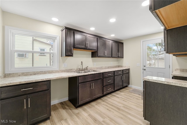 kitchen featuring dark brown cabinets, light wood-type flooring, and sink