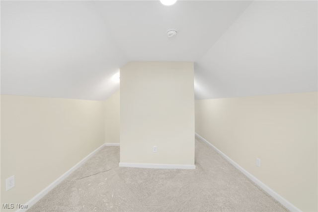 additional living space featuring light colored carpet and vaulted ceiling