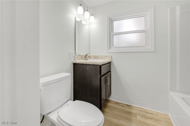 bathroom with wood-type flooring, vanity, and toilet