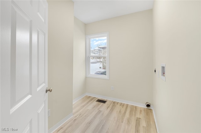 laundry area featuring electric dryer hookup, hookup for a washing machine, and light hardwood / wood-style flooring