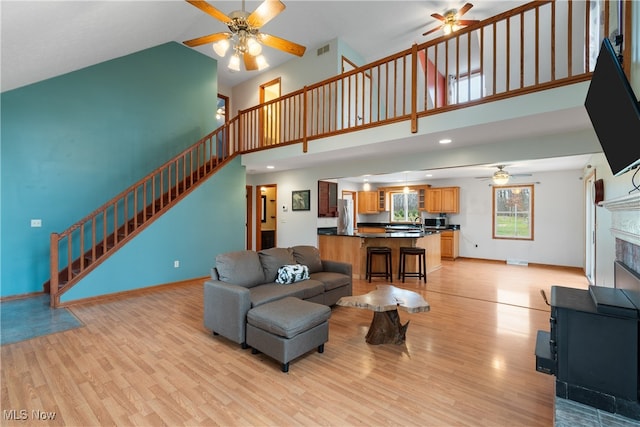 living room with light hardwood / wood-style floors, high vaulted ceiling, and ceiling fan