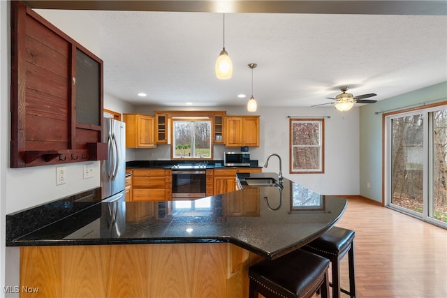 kitchen with a healthy amount of sunlight, kitchen peninsula, sink, and appliances with stainless steel finishes