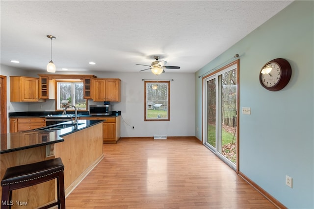 kitchen featuring decorative light fixtures, ceiling fan, light wood-type flooring, and sink