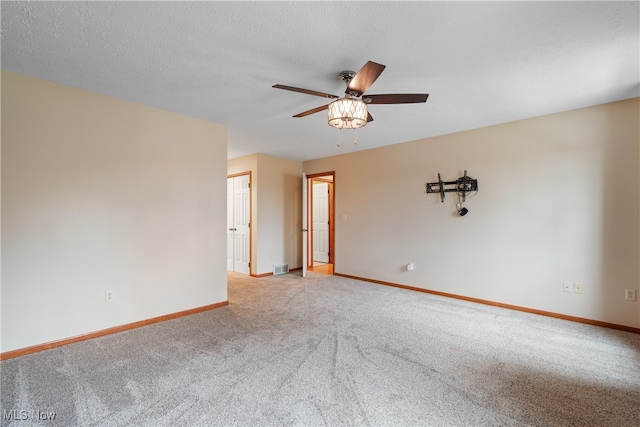 empty room featuring a textured ceiling, light colored carpet, and ceiling fan