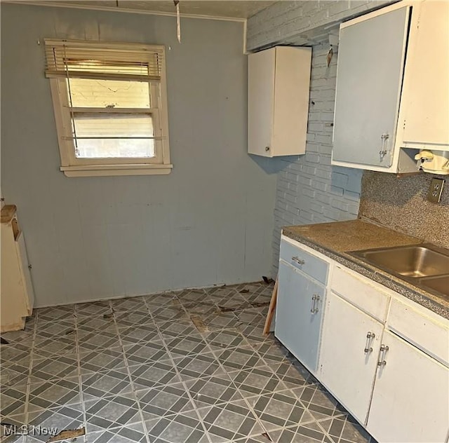 kitchen with white cabinets, decorative backsplash, dark tile patterned floors, and sink