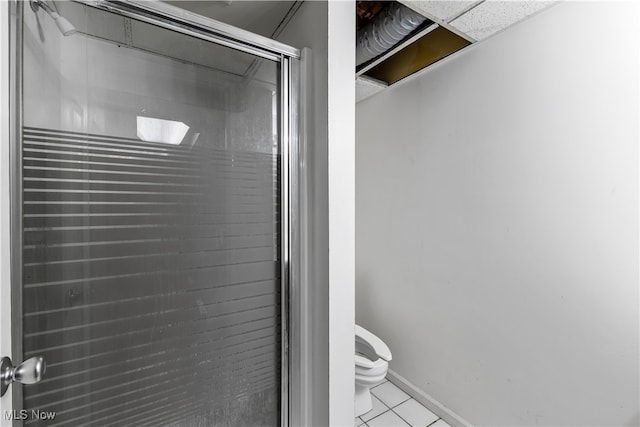 bathroom with tile patterned flooring, a shower with door, and toilet