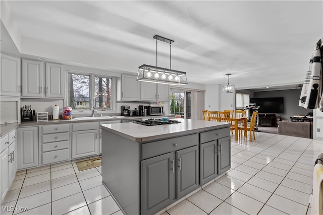 kitchen featuring gray cabinets, a kitchen island, a healthy amount of sunlight, and sink