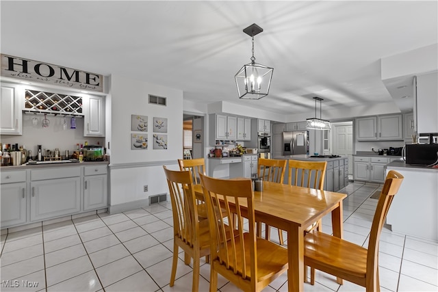 dining space with sink, light tile patterned floors, and an inviting chandelier