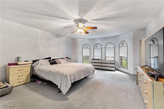 bedroom with ceiling fan, light colored carpet, and multiple windows