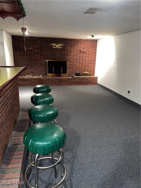 playroom featuring dark carpet and a brick fireplace