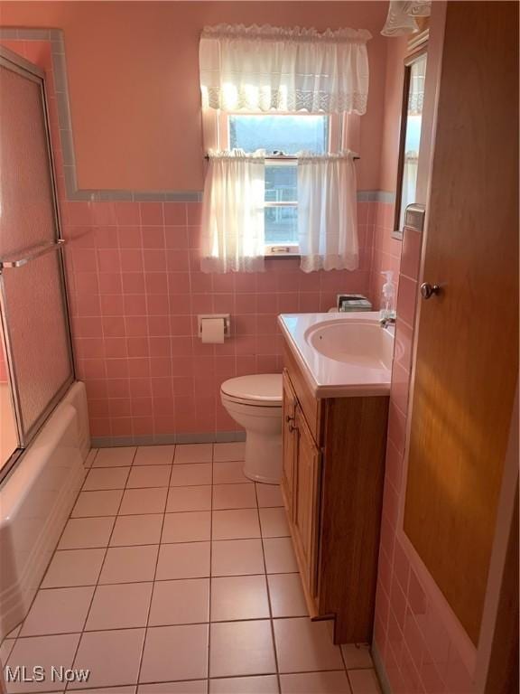 full bathroom featuring tile patterned floors, vanity, a healthy amount of sunlight, and tile walls