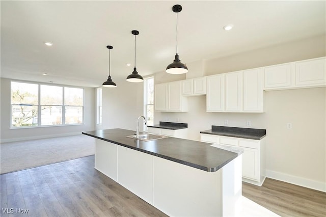 kitchen with a sink, dark countertops, white cabinetry, baseboards, and recessed lighting