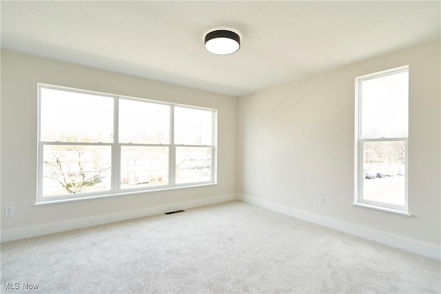 spare room featuring healthy amount of natural light, baseboards, and carpet floors