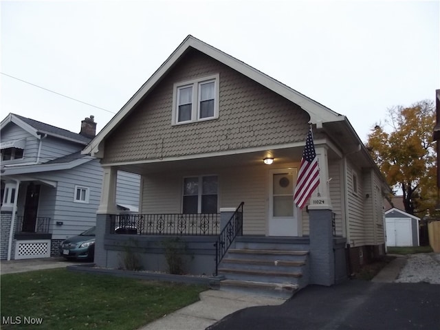 bungalow with covered porch and a storage unit