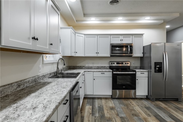 kitchen with white cabinetry, sink, light stone countertops, dark hardwood / wood-style flooring, and appliances with stainless steel finishes