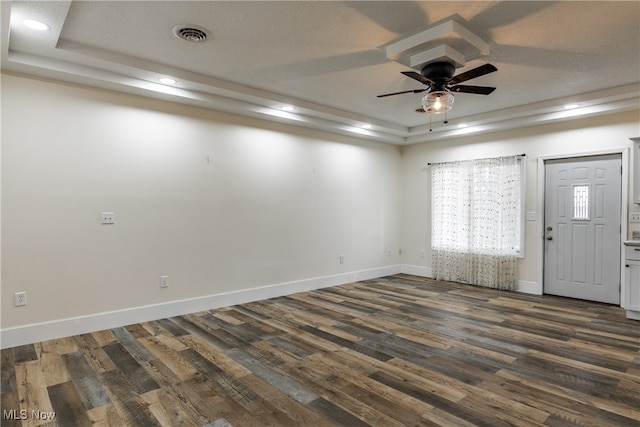 empty room featuring a raised ceiling, ceiling fan, a textured ceiling, and dark hardwood / wood-style floors