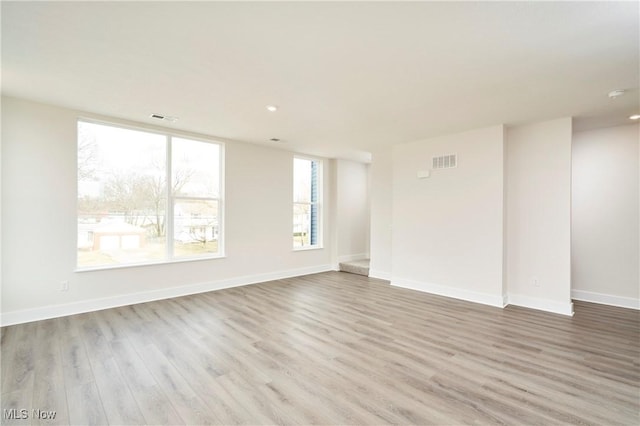 unfurnished room with wood finished floors, visible vents, and baseboards