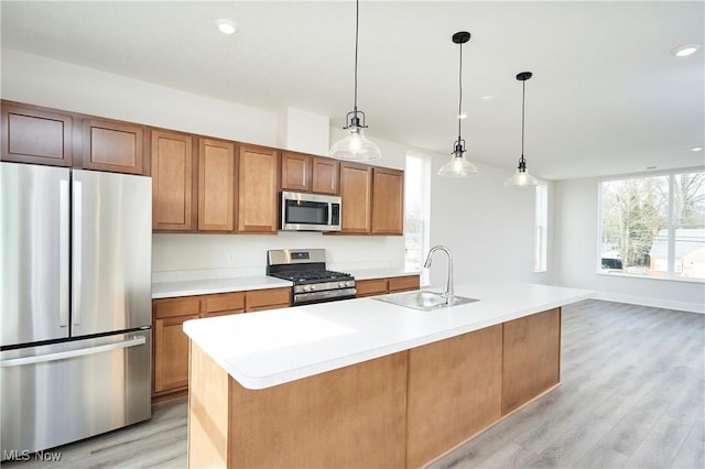 kitchen with a sink, light countertops, light wood-style floors, and stainless steel appliances